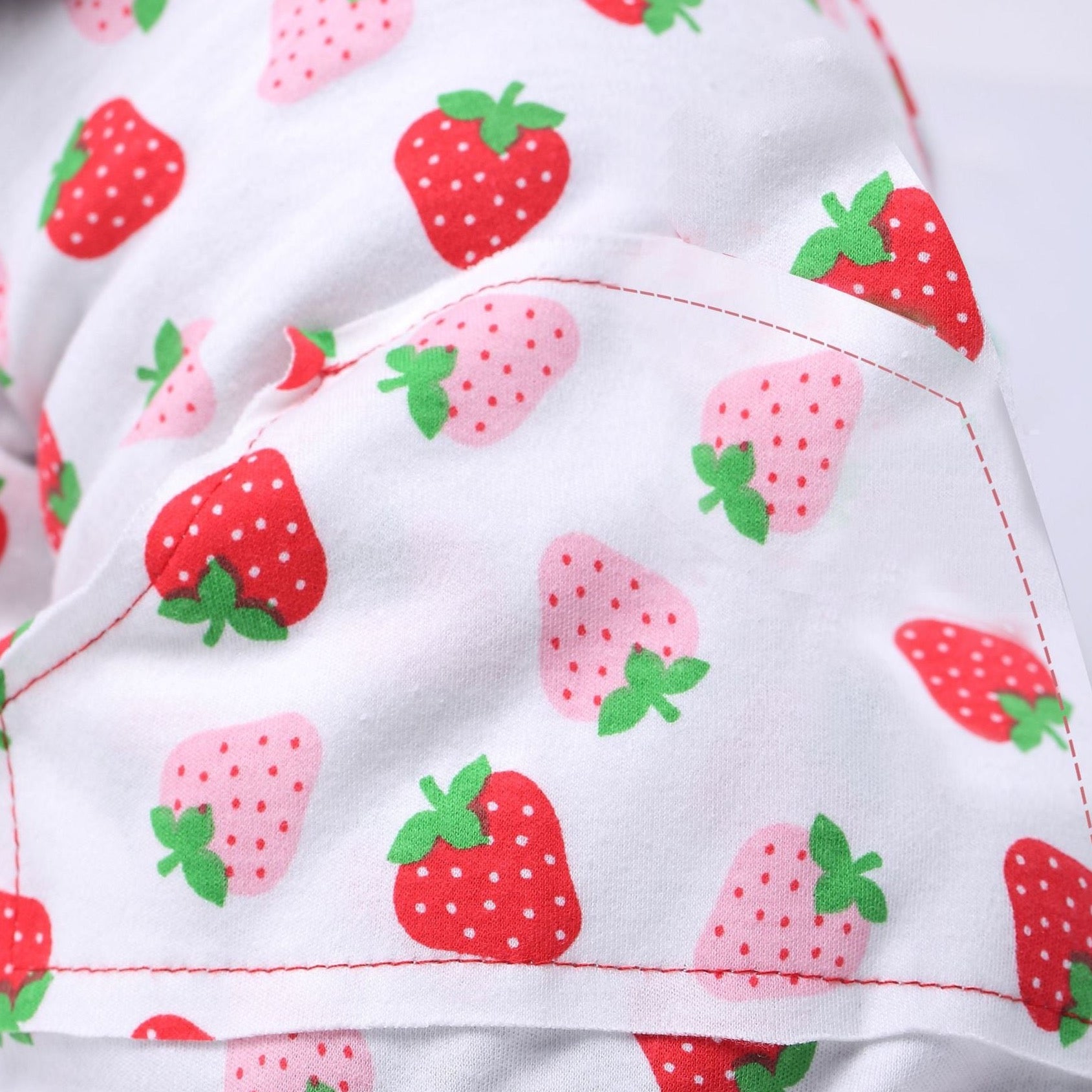Red and pink polka-dot strawberries on white fabric